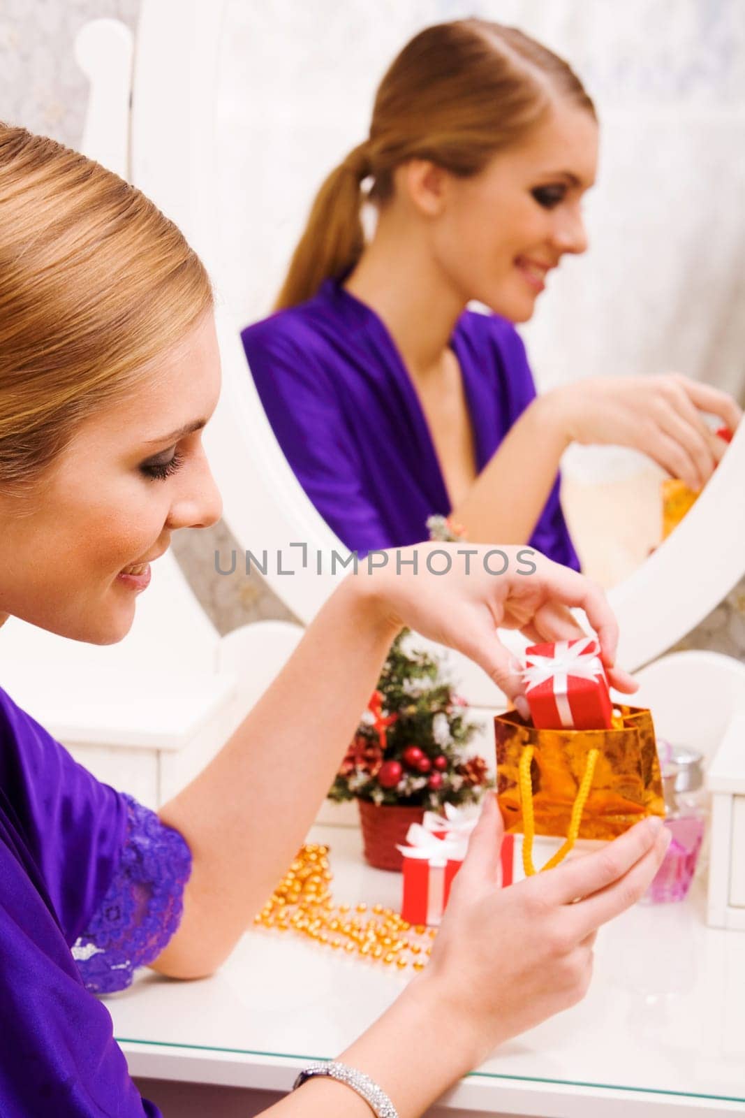 Portrait of happy girl putting small giftbox into golden package