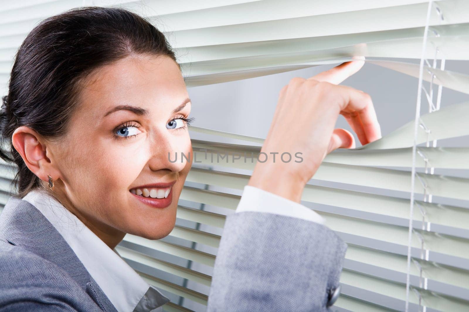 Young pretty woman looking through white jalousie