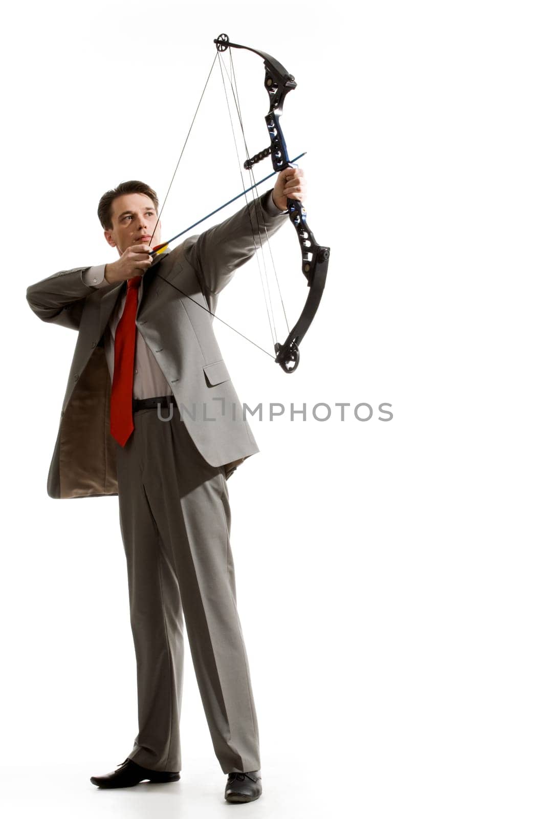 Portrait of courageous businessman holding crossbow and aiming at target