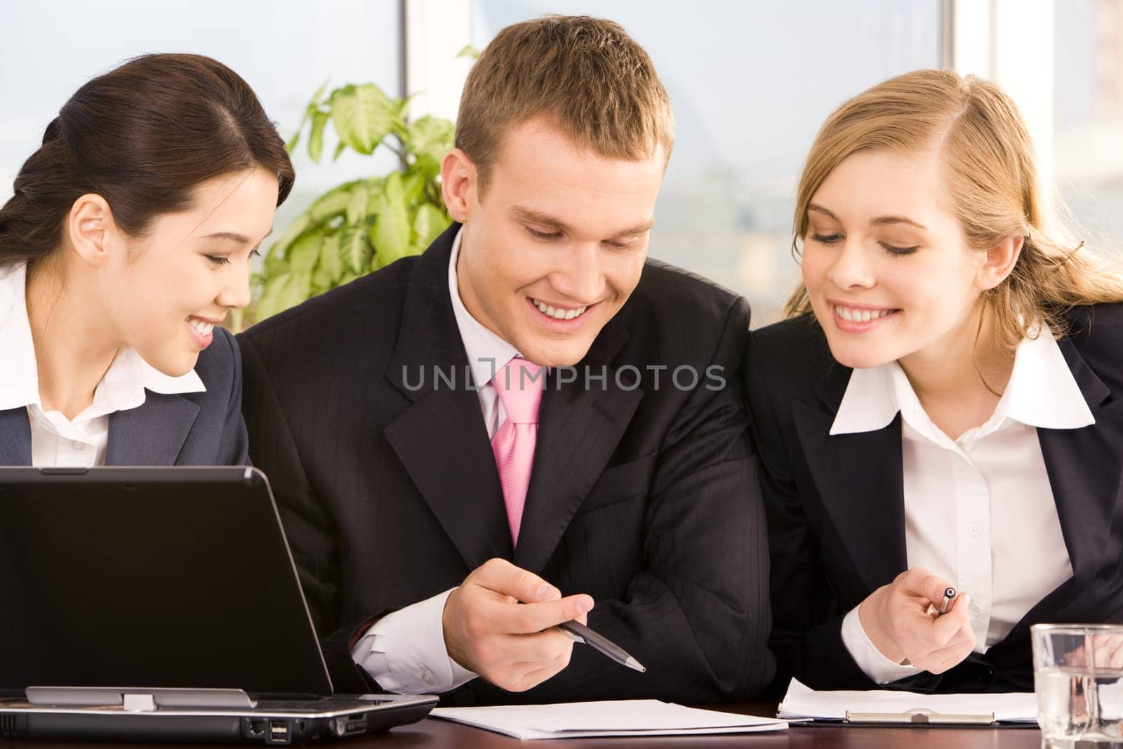 Portrait of business group discussing papers at table in the office with pens in hands