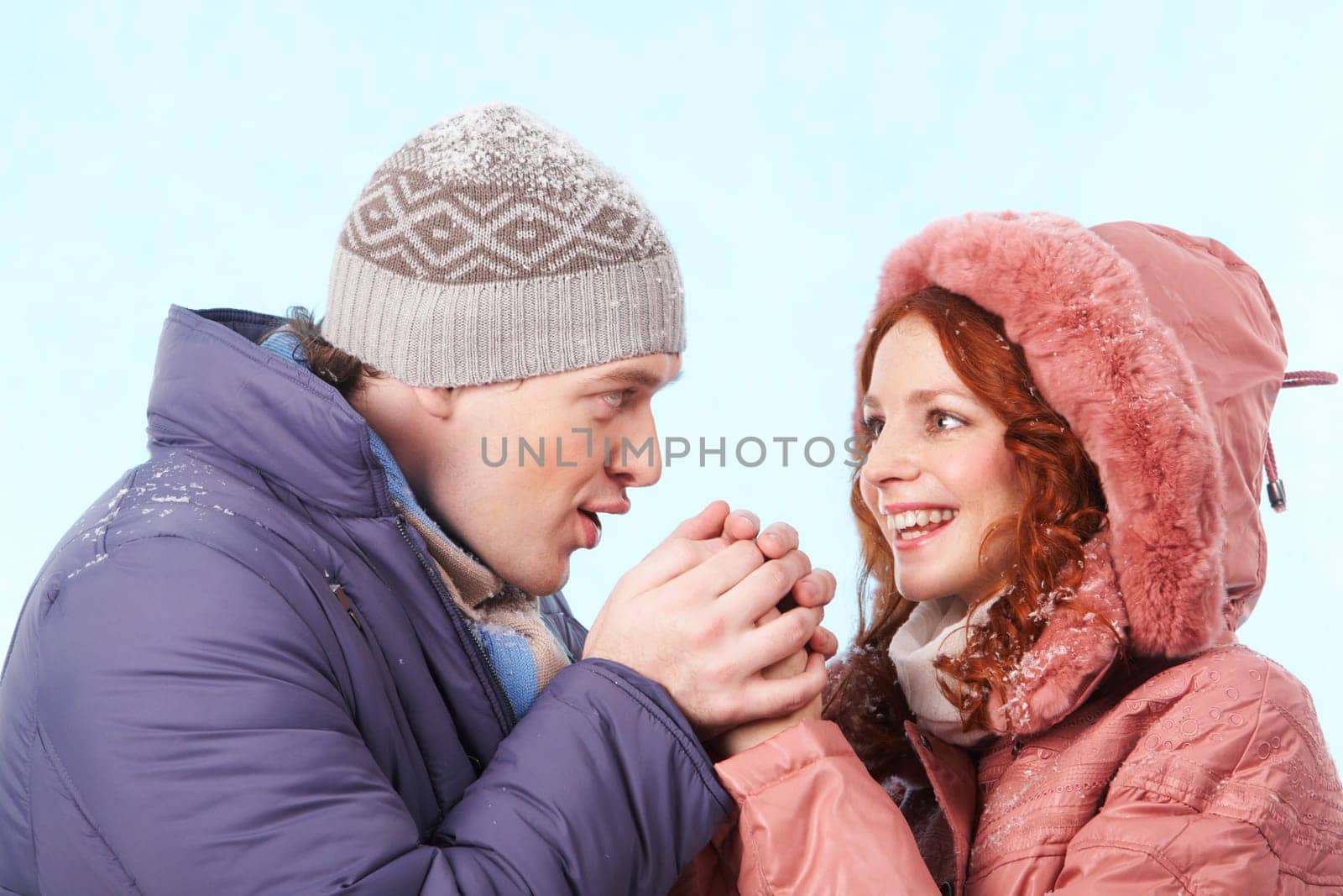 Portrait of careful young man warming up his girlfriend hands