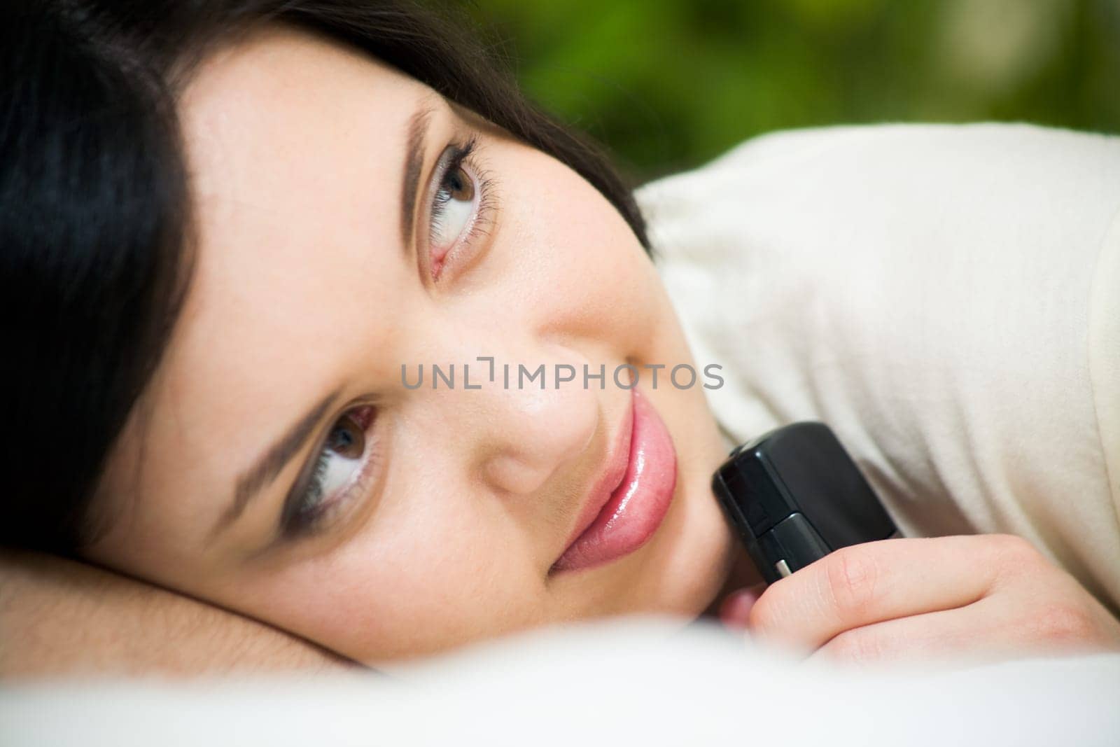 Face of charming girl holding telephone by her chin and looking aside