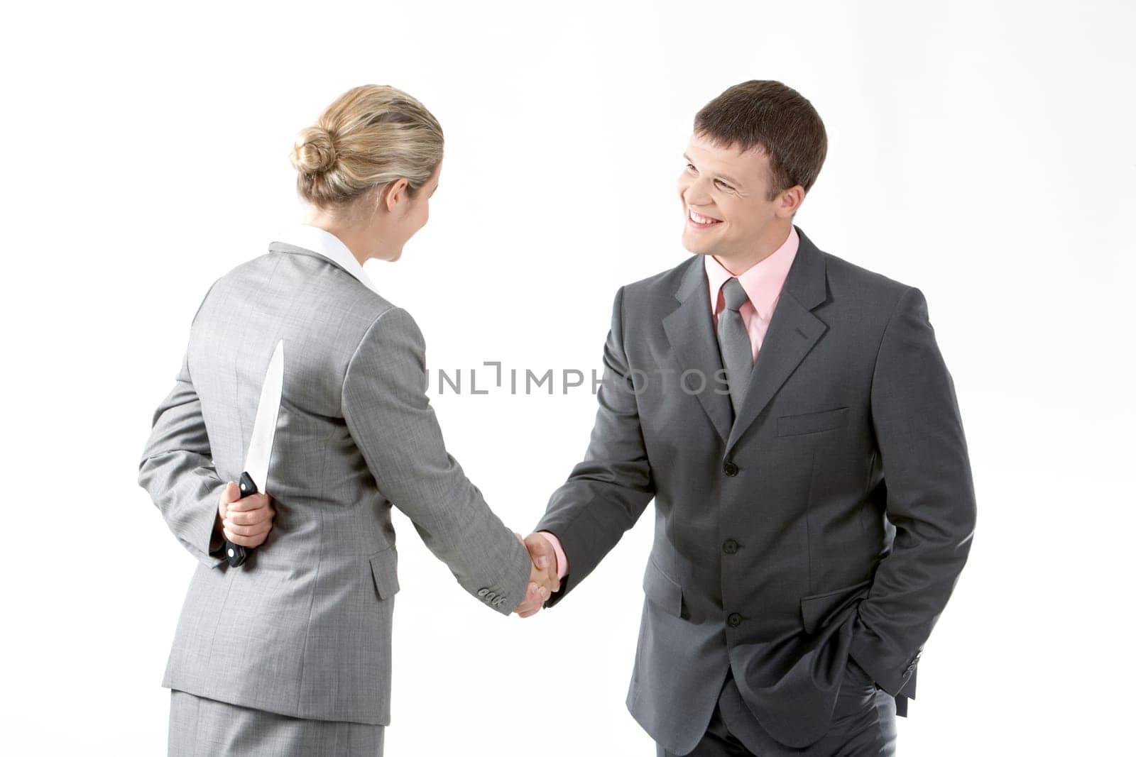 Portrait of business partners handshaking while female holding knife behind her back
