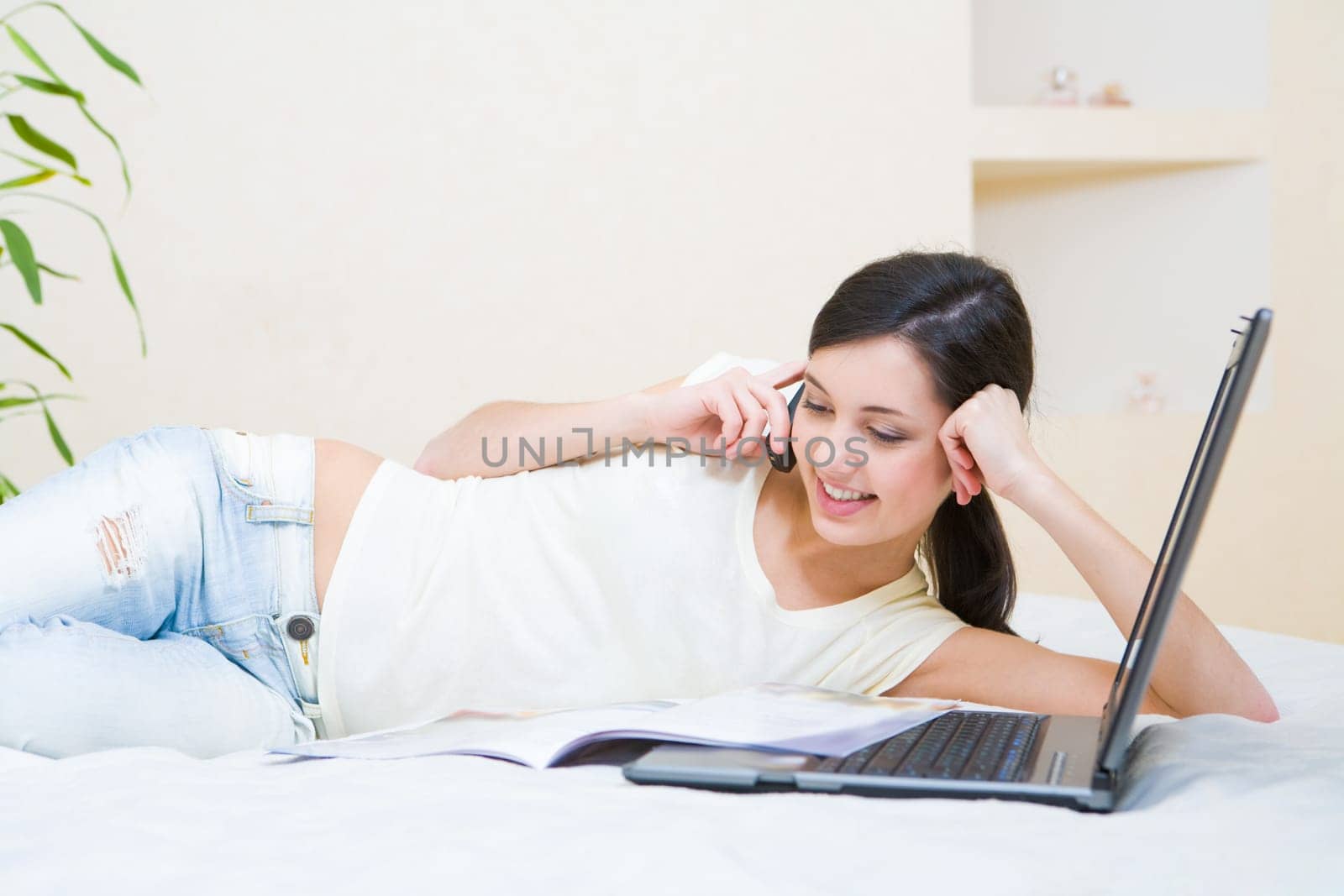 Photo of attractive teenage girl talking on the phone while looking into a book