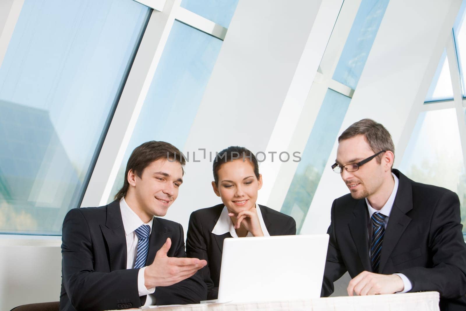 Portrait of executive employees looking at laptop monitor with smiles and communicating