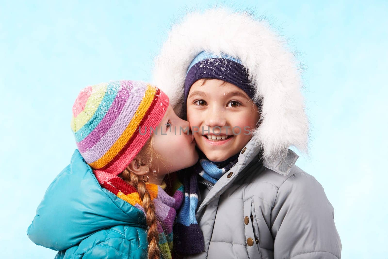 Portrait of happy child smiling at camers while being kissed by pretty girl