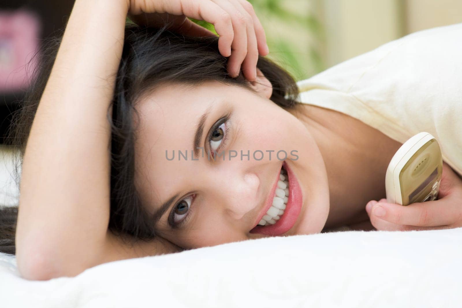 Pretty young female relaxing on bed and looking at camera