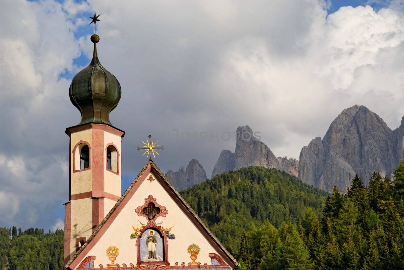 Small Church of St. John in Ranui with Odle Mountains and a dramatic cloudy sky,Funes Valley,Dolomites,Suedtitol,Italy