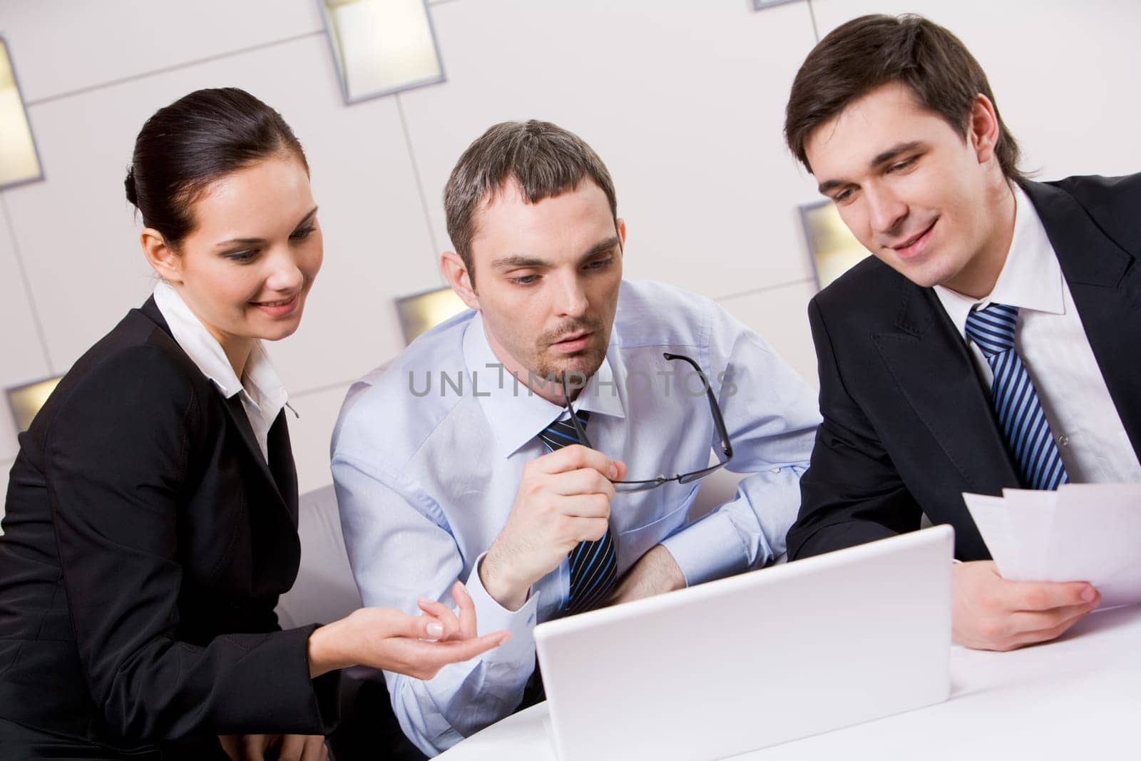 Portrait of executive employees looking at laptop monitor with pensive boss between them and discussing new project
