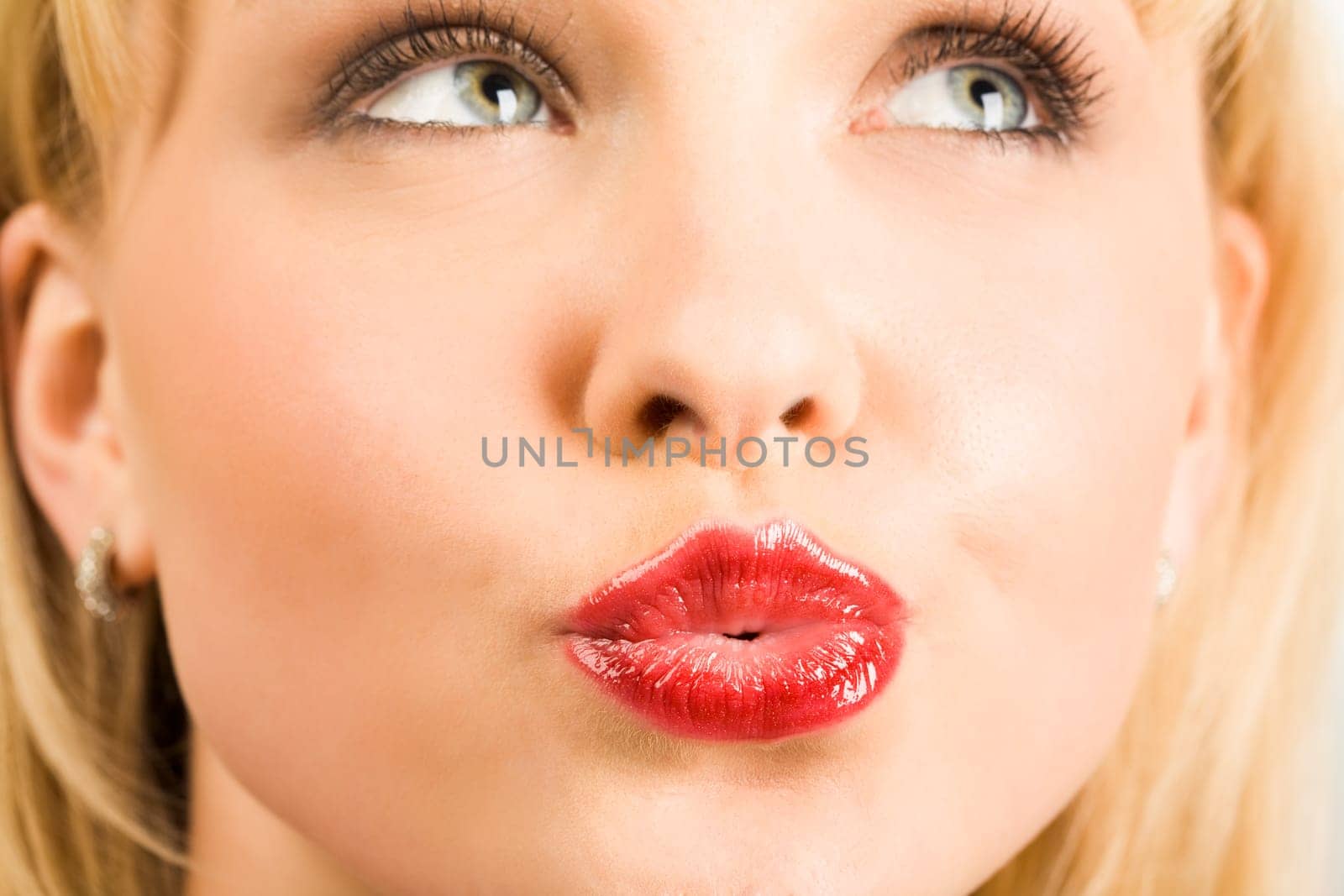 Close-up of pretty blonde looking aside with her lips fixed in kiss
