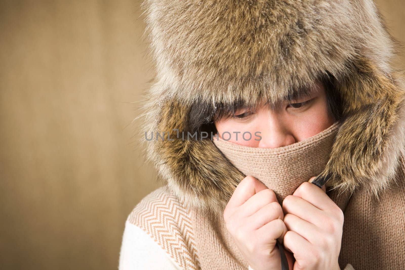 Portrait of cold man in fur hat and knitted scarf warming up