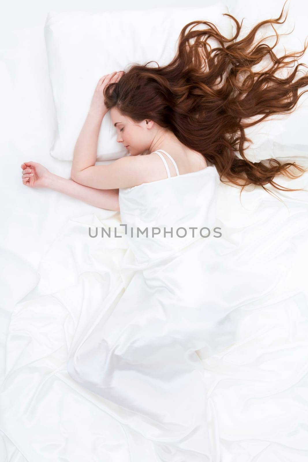 Image of peaceful girl lying on linen bed under satin cloth and dreaming