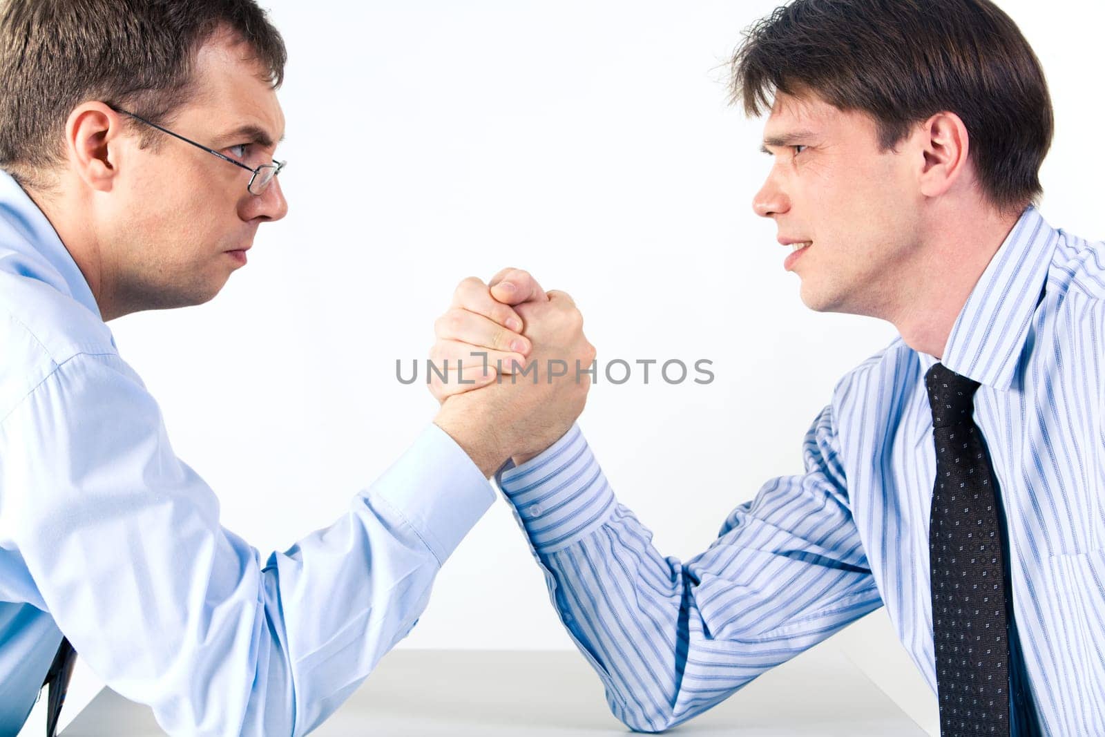 Portrait of two businessmen sitting opposite each other elbowing on the table with their arms grappled in fight