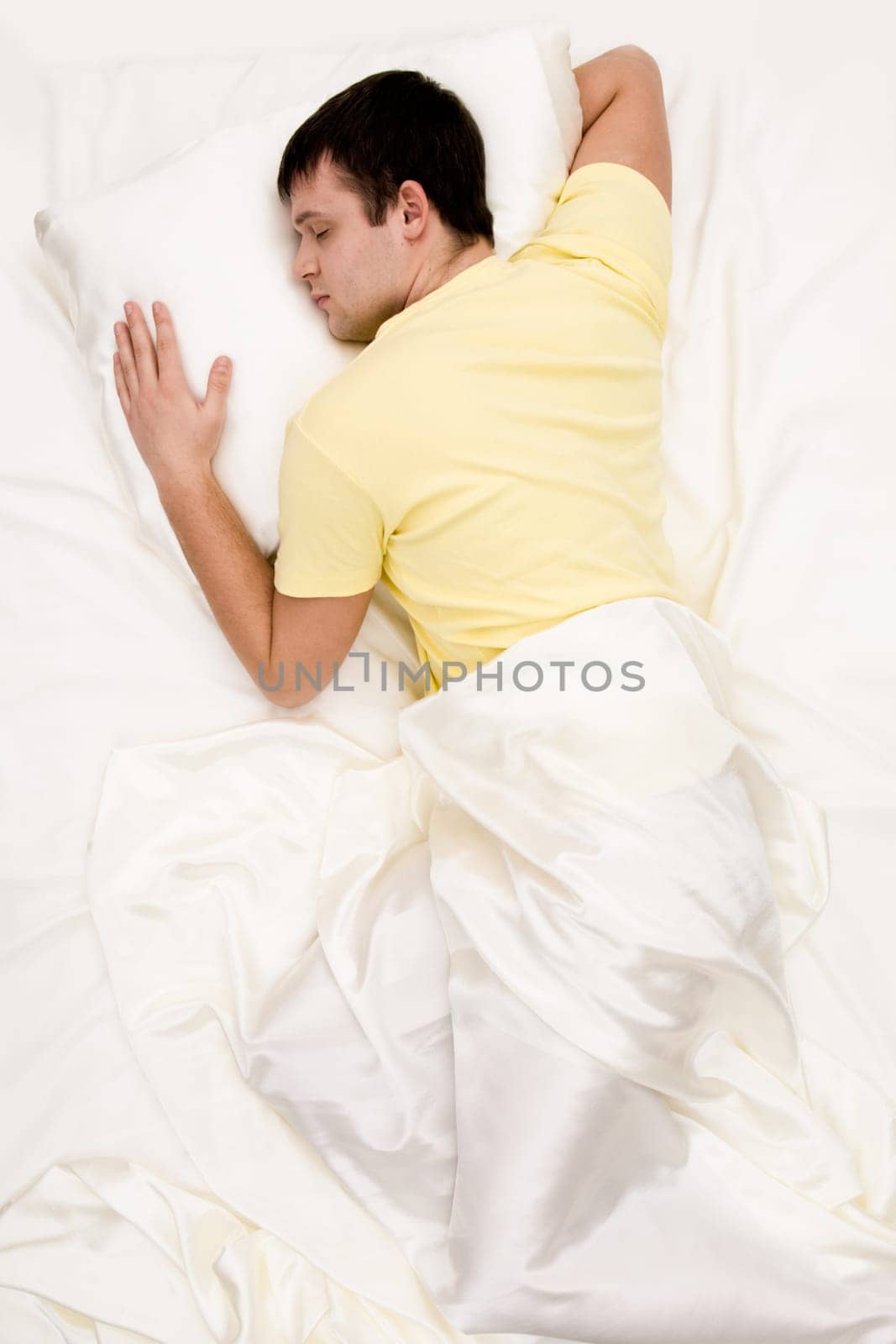Shot from above of tranquil male sleeping in comfortable bed at night