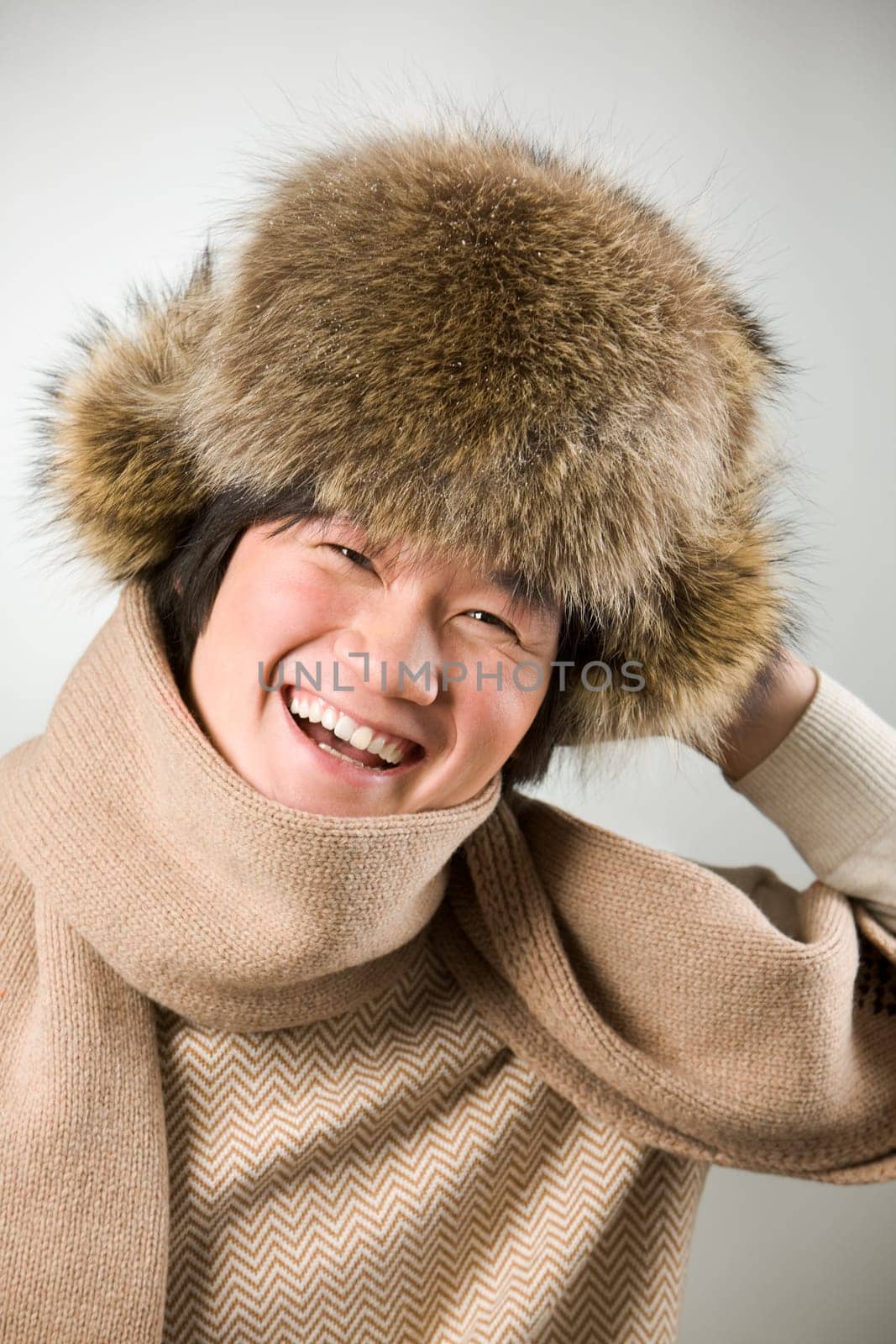 Portrait of happy man in warm fur hat and white sweater laughing