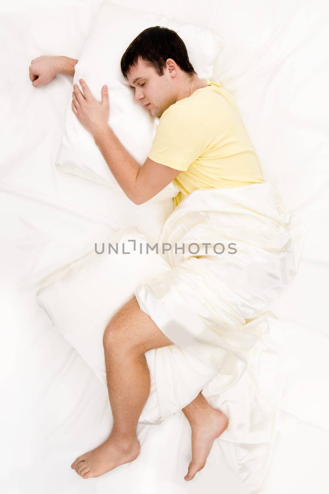 Above view of peaceful man having pleasant sleep on his comfortable bed