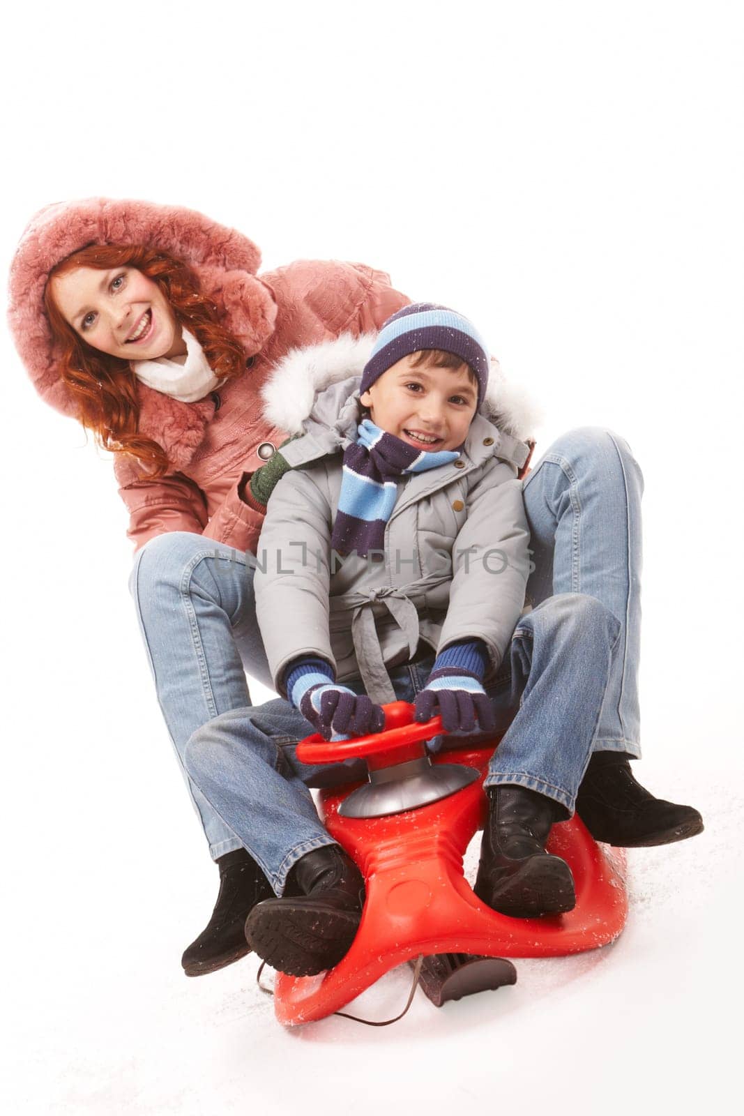 Happy boy and his mother sitting on sledge and having fun