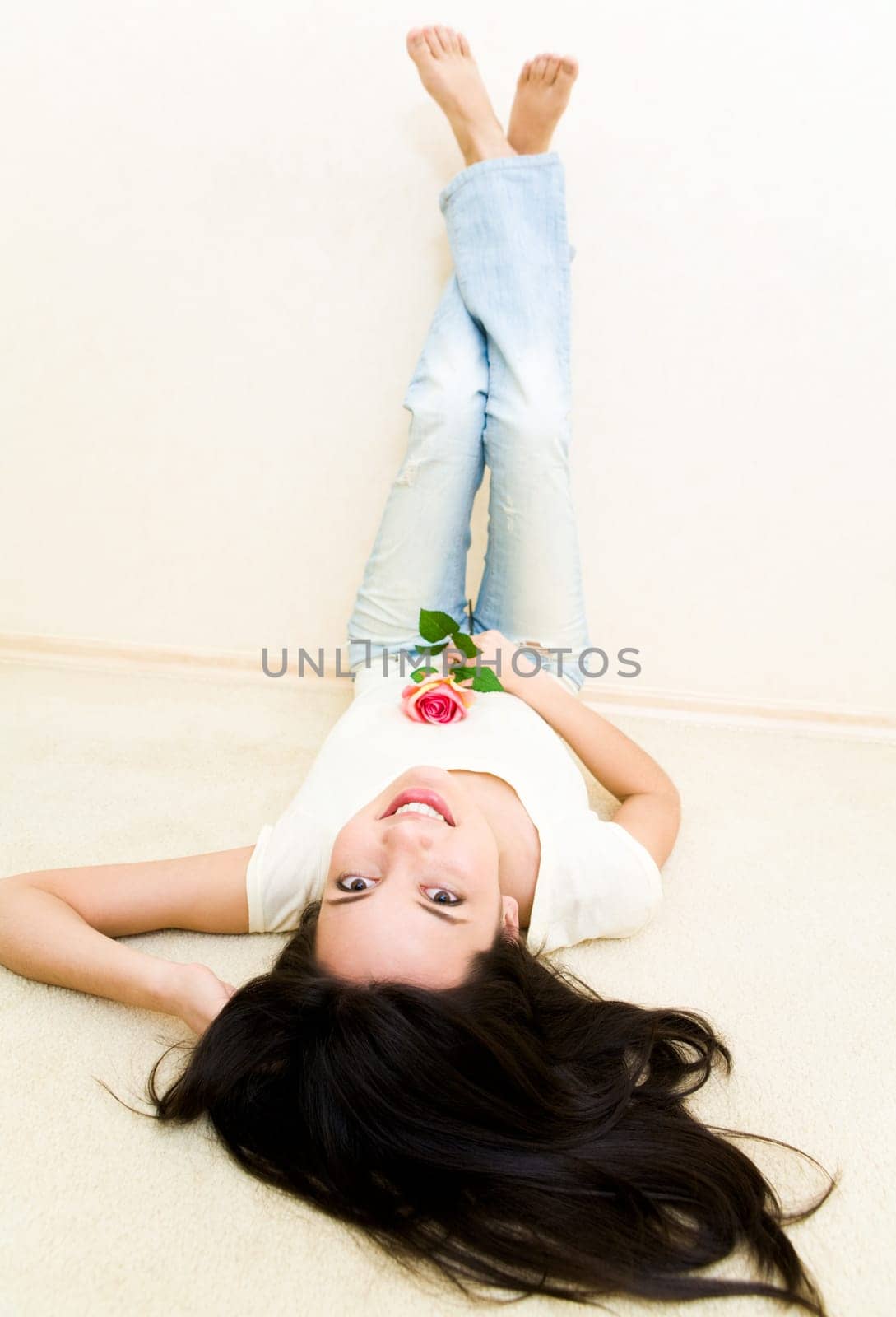 Cute girl lying on the floor with her legs against wall and looking at camera