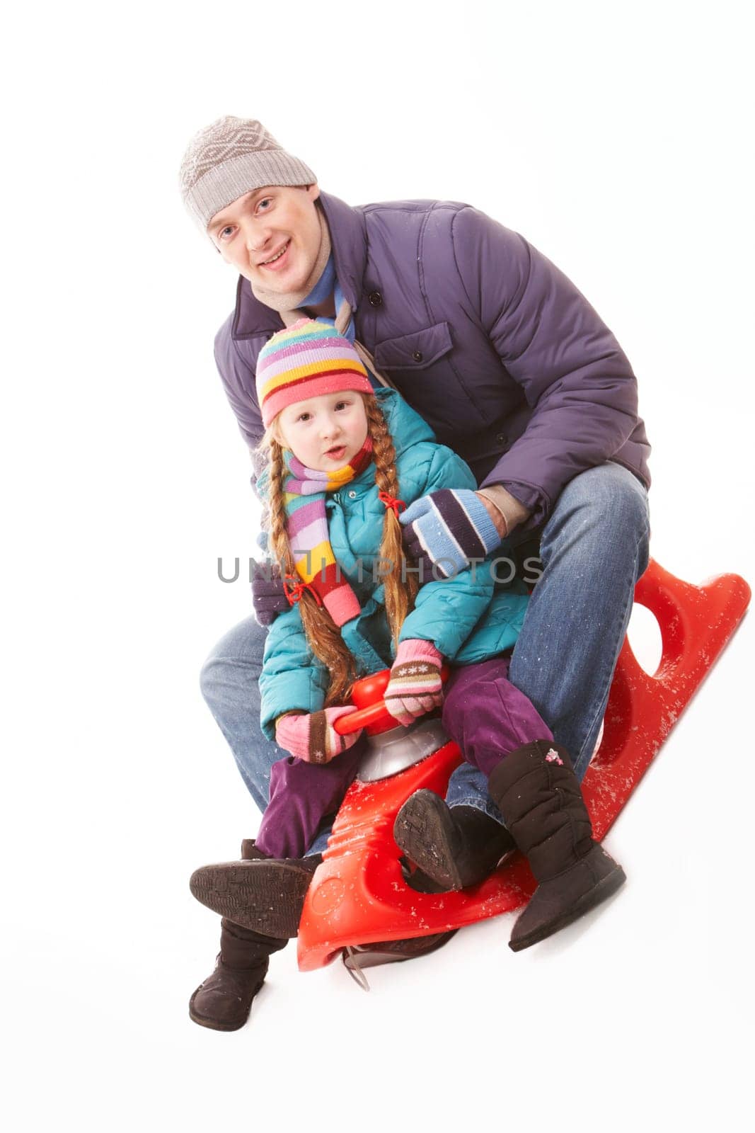 Happy girl and her father sitting on sledge and having fun