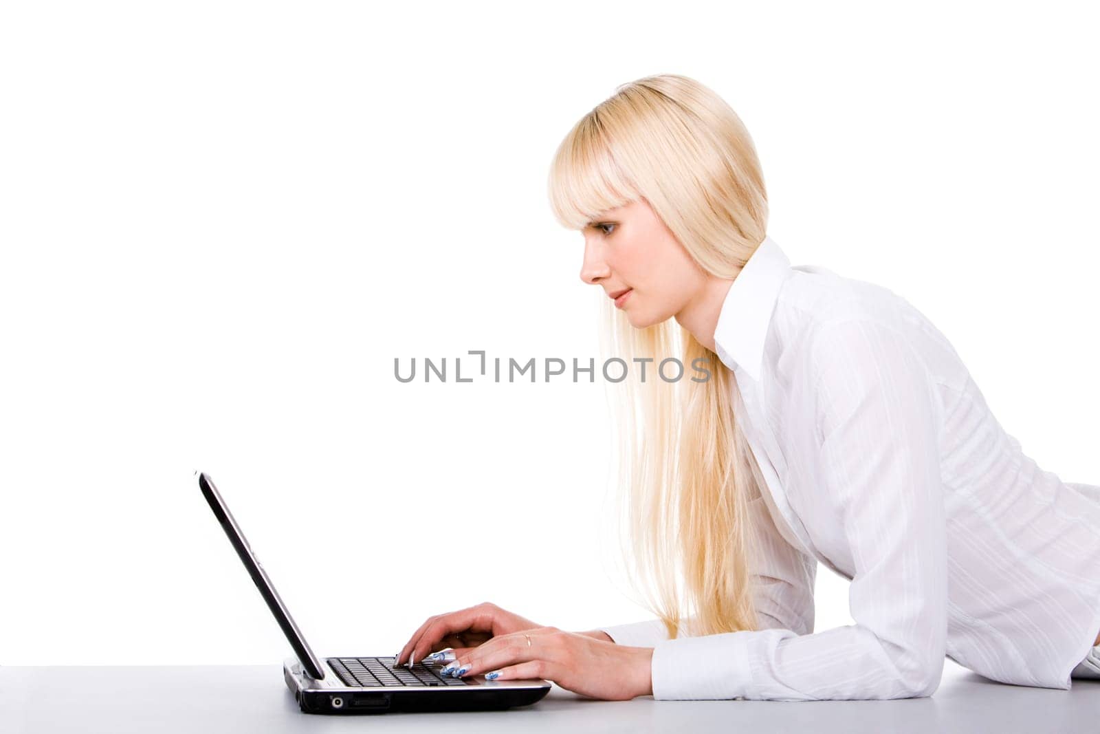 Image of pretty female lying before laptop and typing
