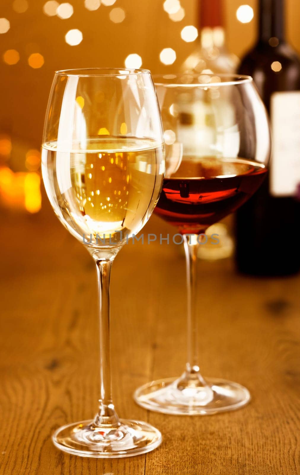 Celebrating with glasses of red and white wine against a sparkling bokeh of festive party lights