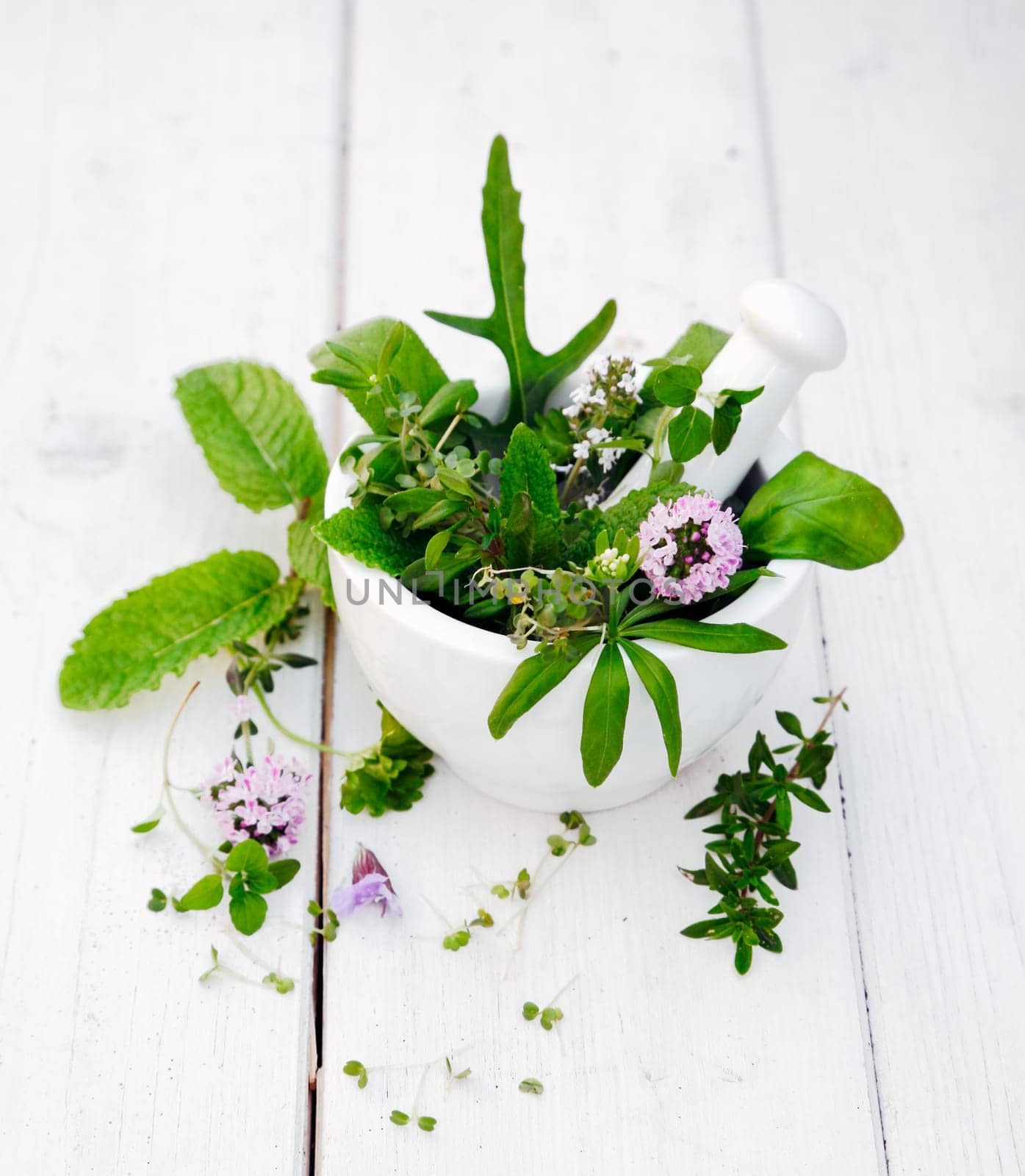Flowering Assorted Herbs in a Mortar with pestle on white wooden background