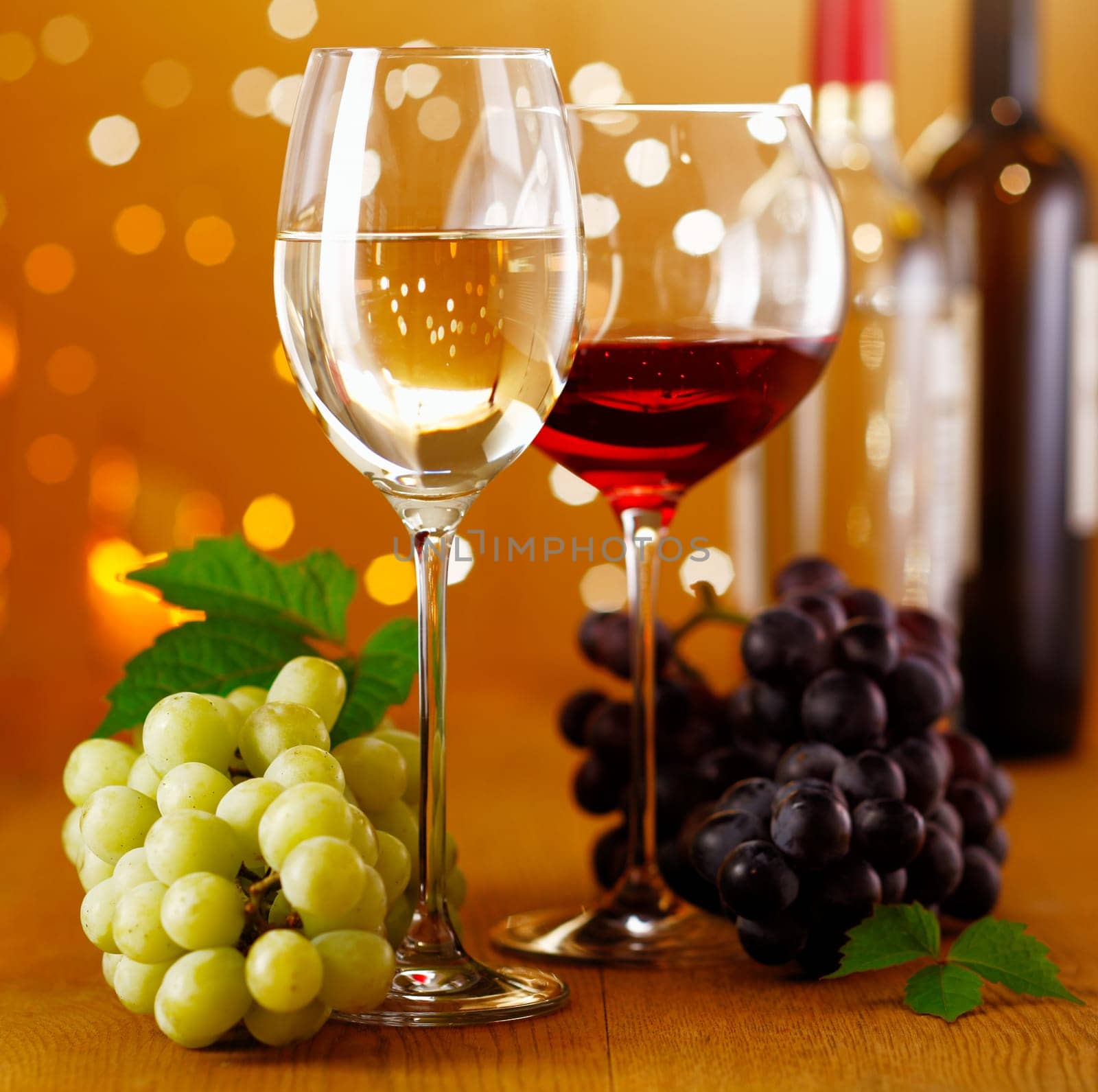 A Glass of festive Red and White Wine and green and blue grapes on a rustic wooden board.