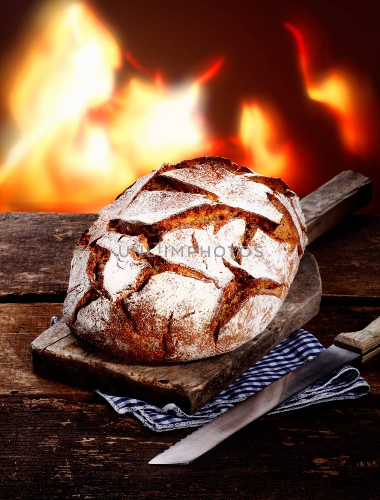 Rye bread on a rustic wooden cutting board on an old country table in front of the fire