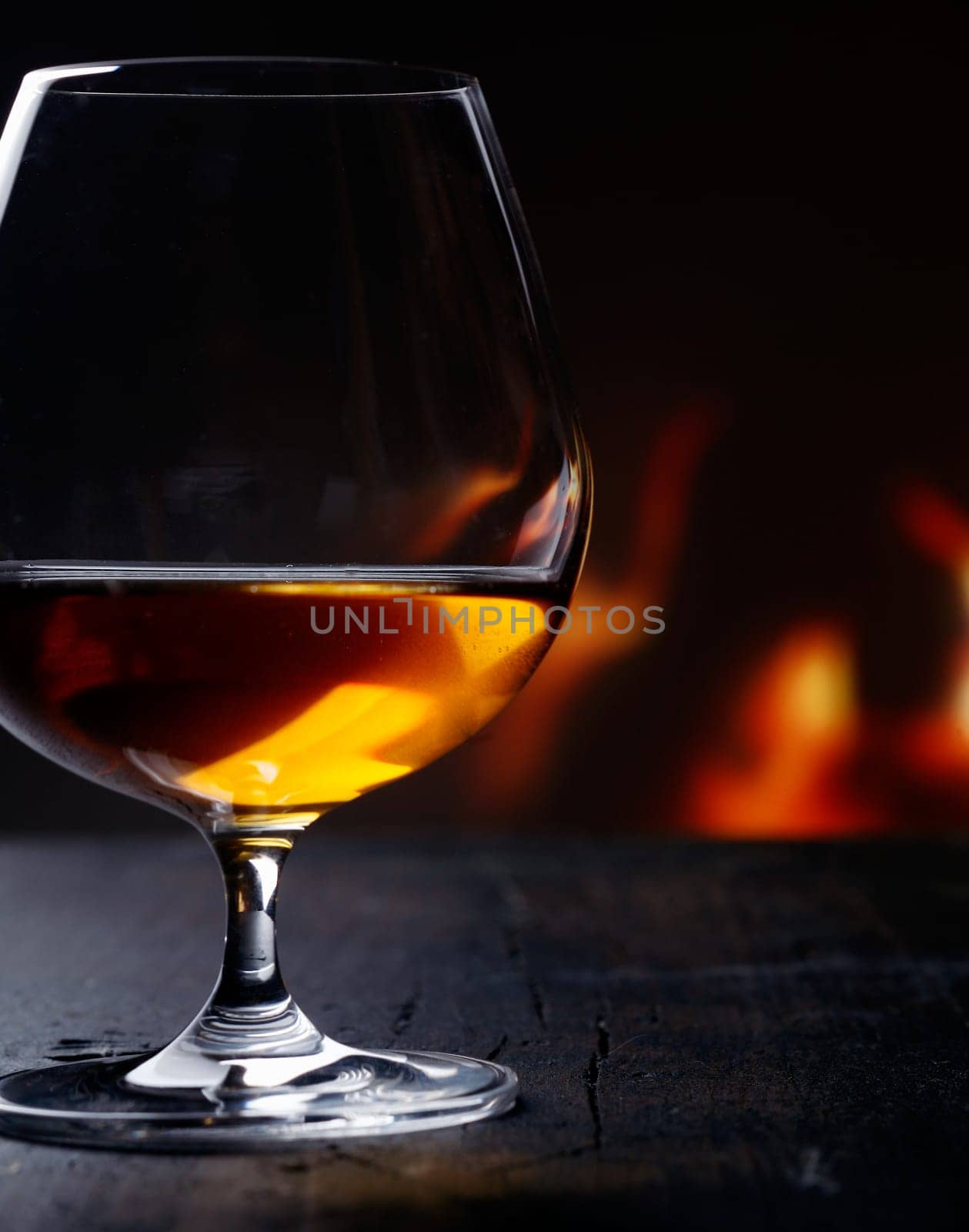 Brandy snifter warming before a glowing fire on an enjoyable and entertaining night out on the town