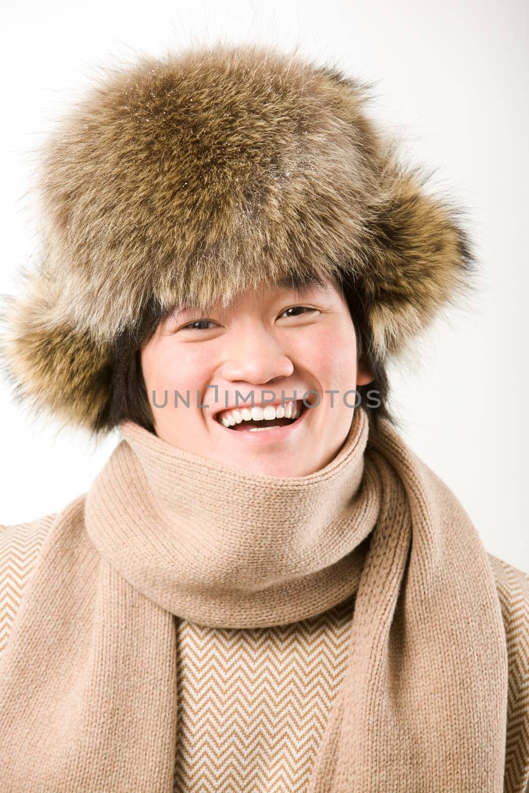 Portrait of happy man in warm fur hat and white sweater laughing