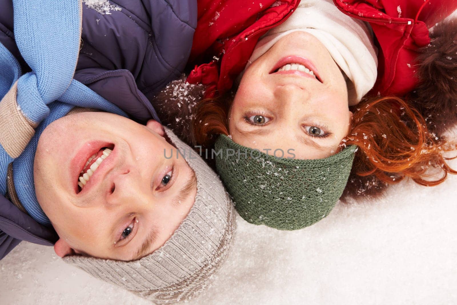 Above shot of happy young couple lying in snow