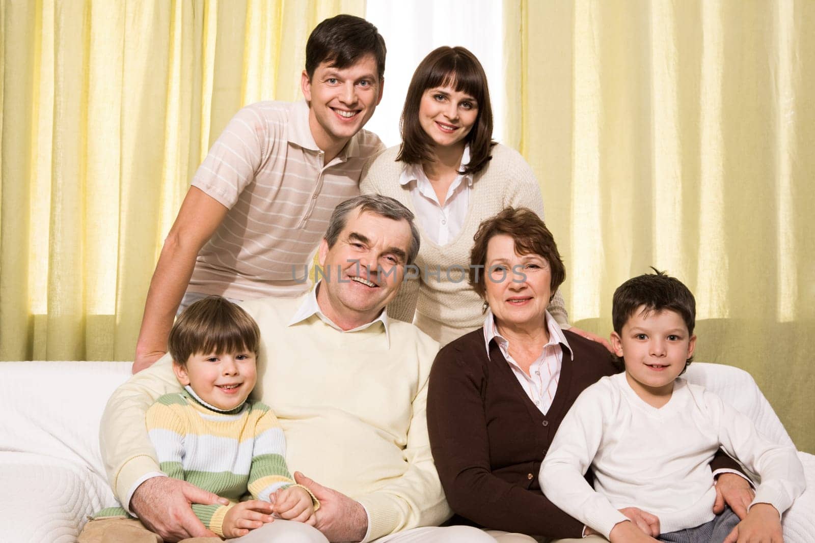 Portrait of senior and young couples with their children looking at camera at home