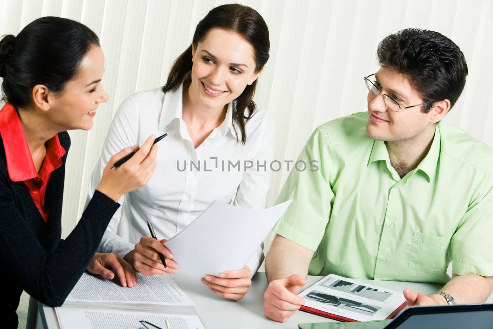 Photo of smart business team sitting around table and discussing documents in the office