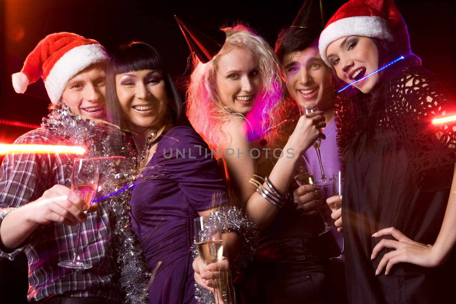 Company of friends clubbing at disco with flutes of champagne in hands