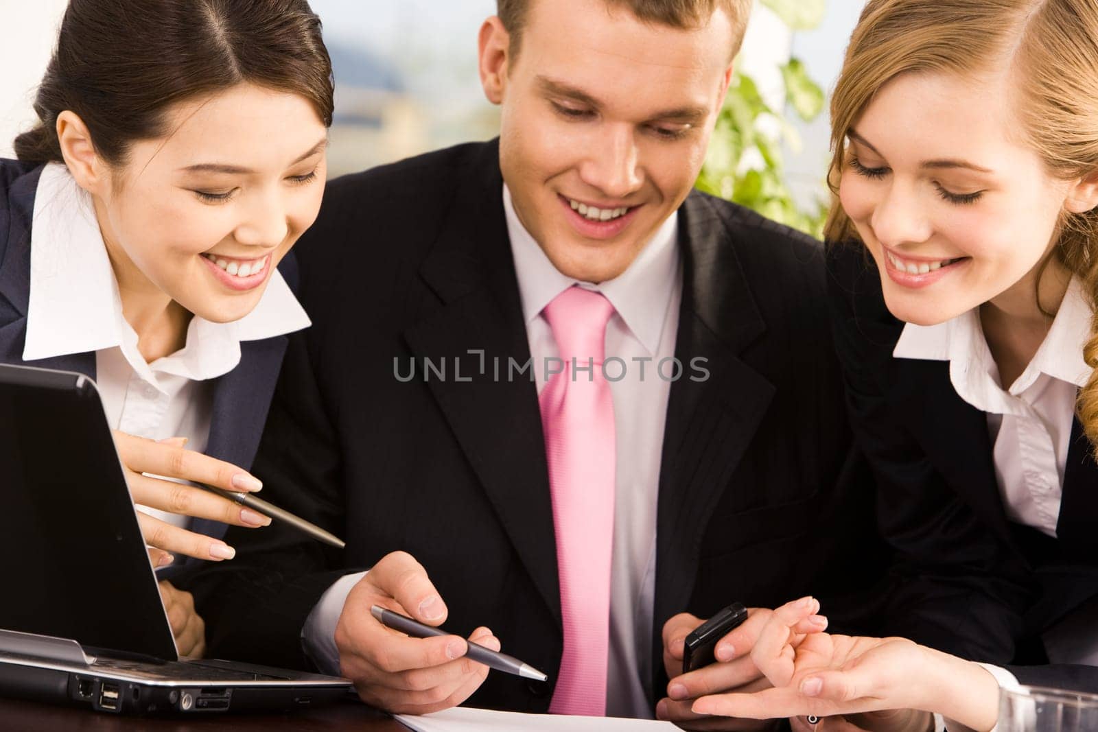 Photo of young businessman between two smart women pointing at document during meeting