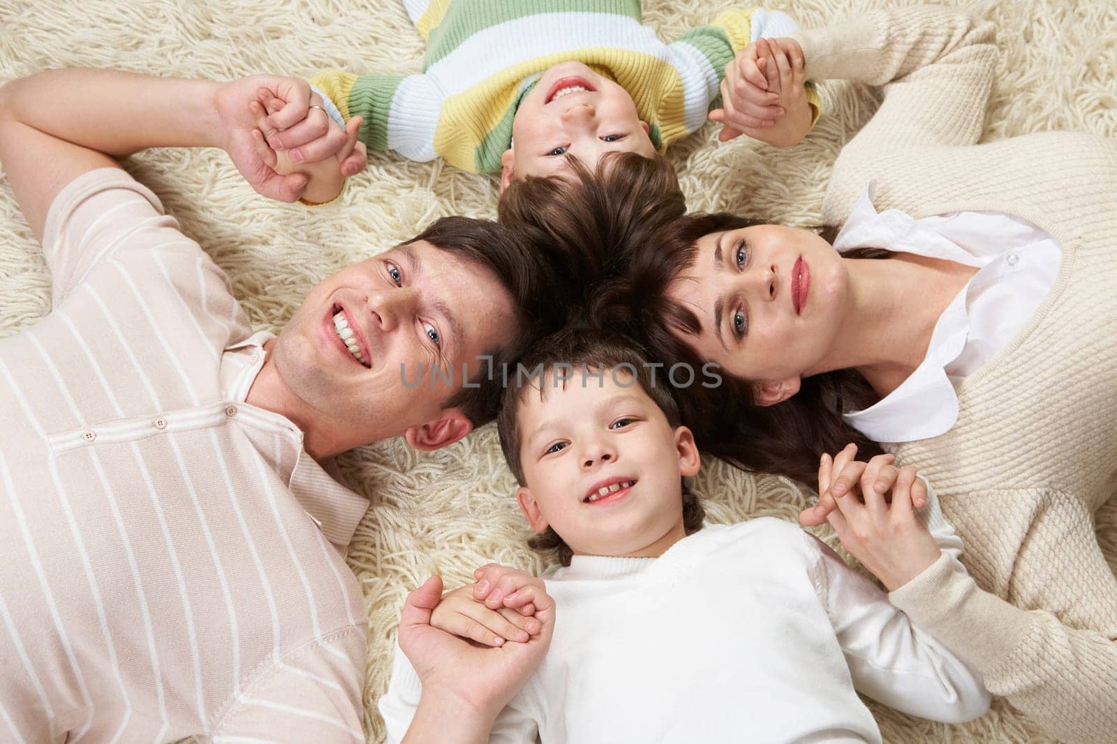 A happy family holding on carpet with clutched hands