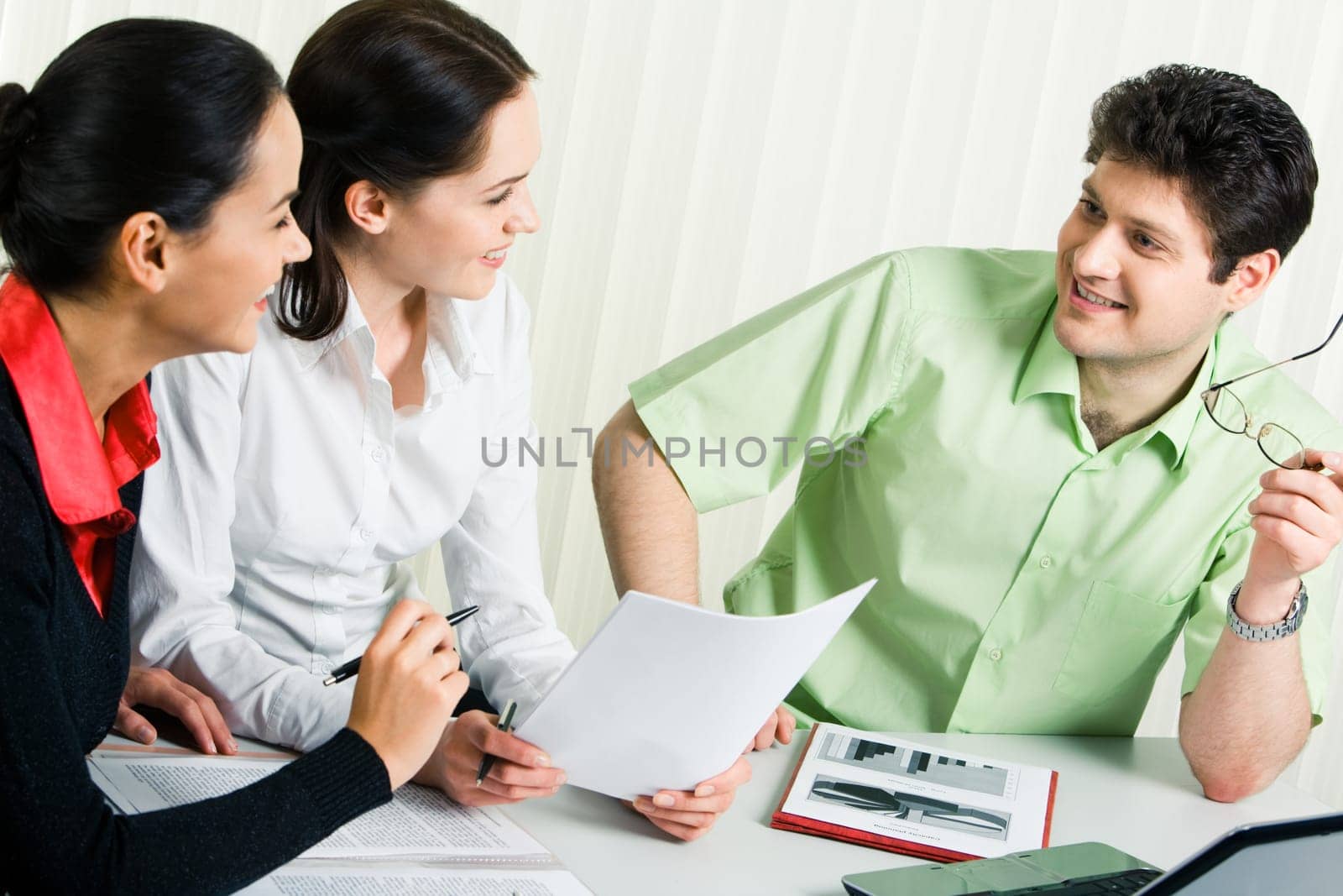 Photo of confident businessman voicing his working ideas while two smiling ladies listening to him attentively