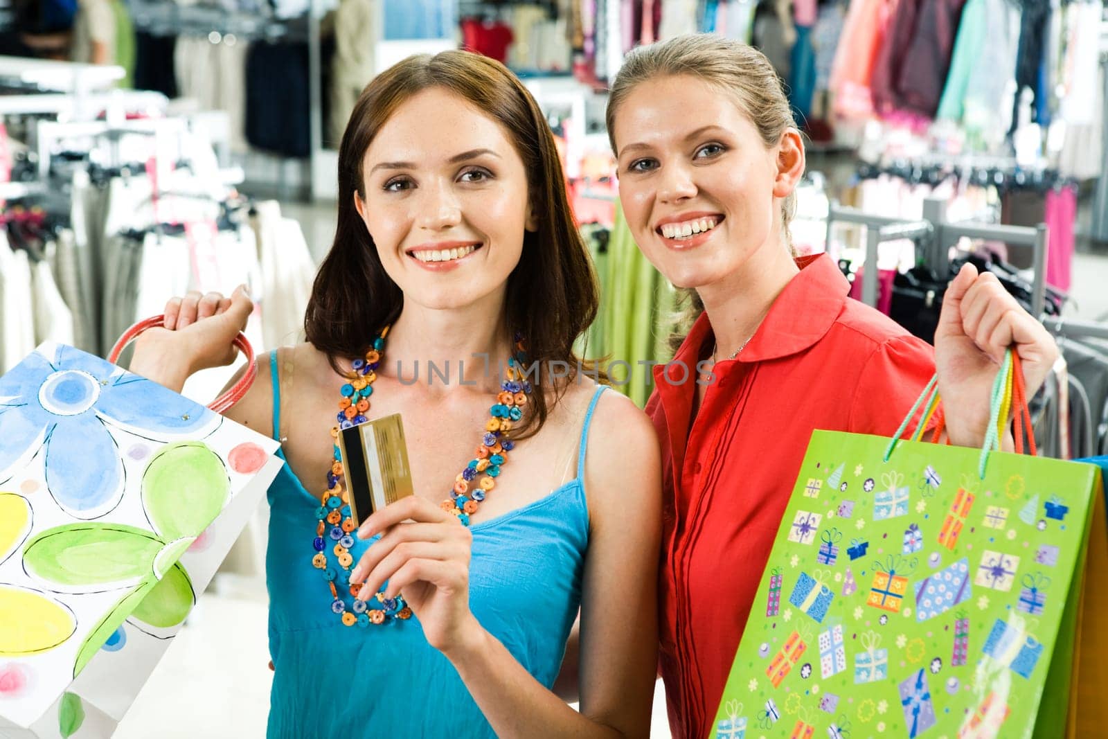 Portrait of elegant women with bags looking at camera in trade center