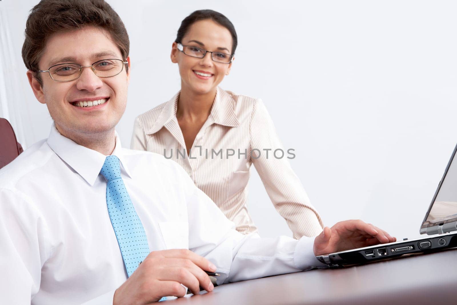Photo of smiling confident boss looking at camera with woman sitting near by