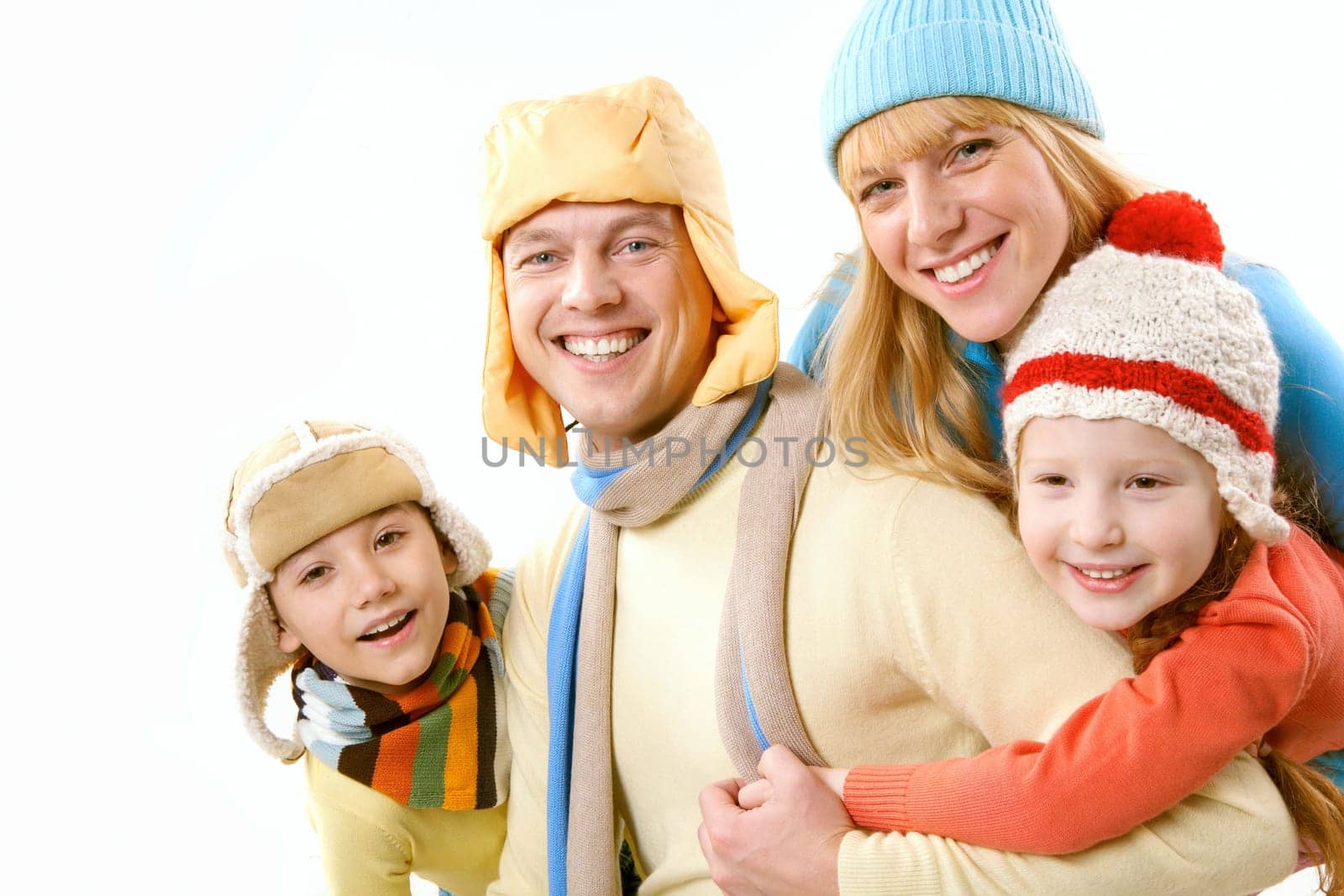 Two children and wife in winter clothes embracing a happy man on white background