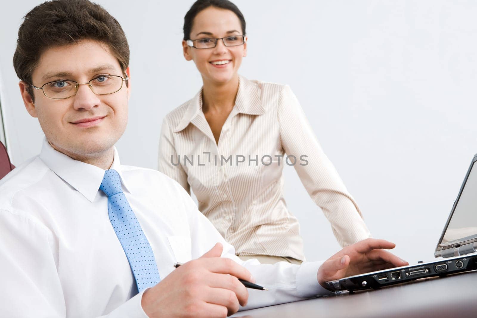 Photo of smiling confident boss looking at camera with woman sitting near by