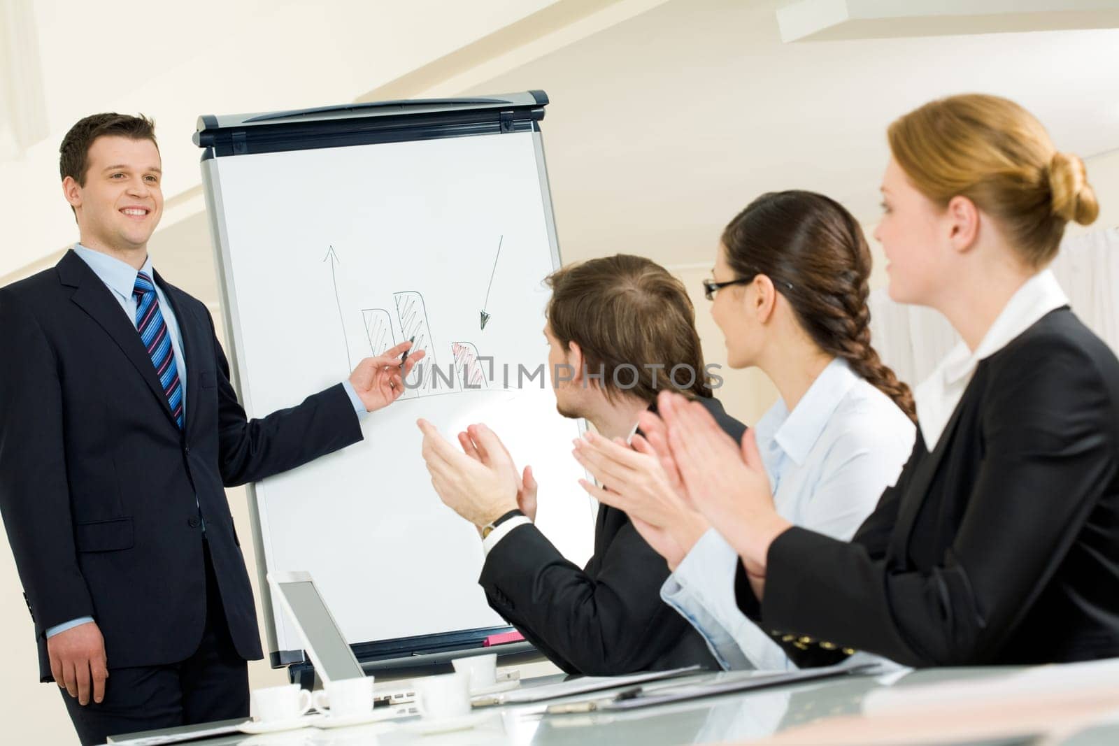 Photo of happy businessman standing by whiteboard while partners applauding to him after successful presentation