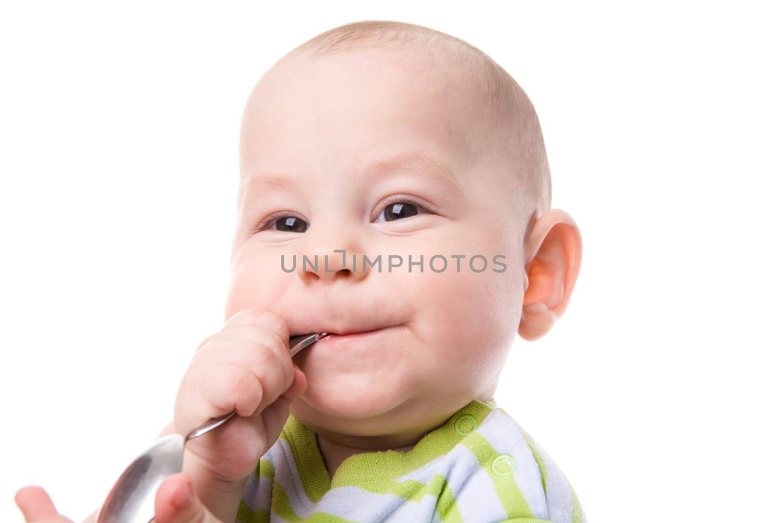 Portrait of cute boy with spoon in mouth and smile on his face