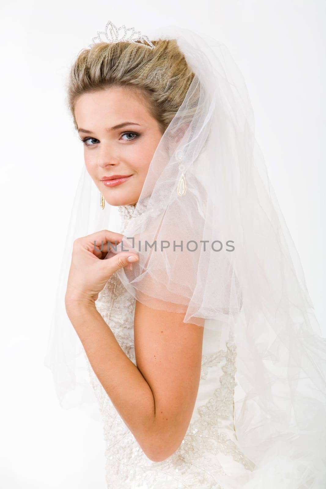 Portrait of pretty bride wearing veil and touching it while looking at camera