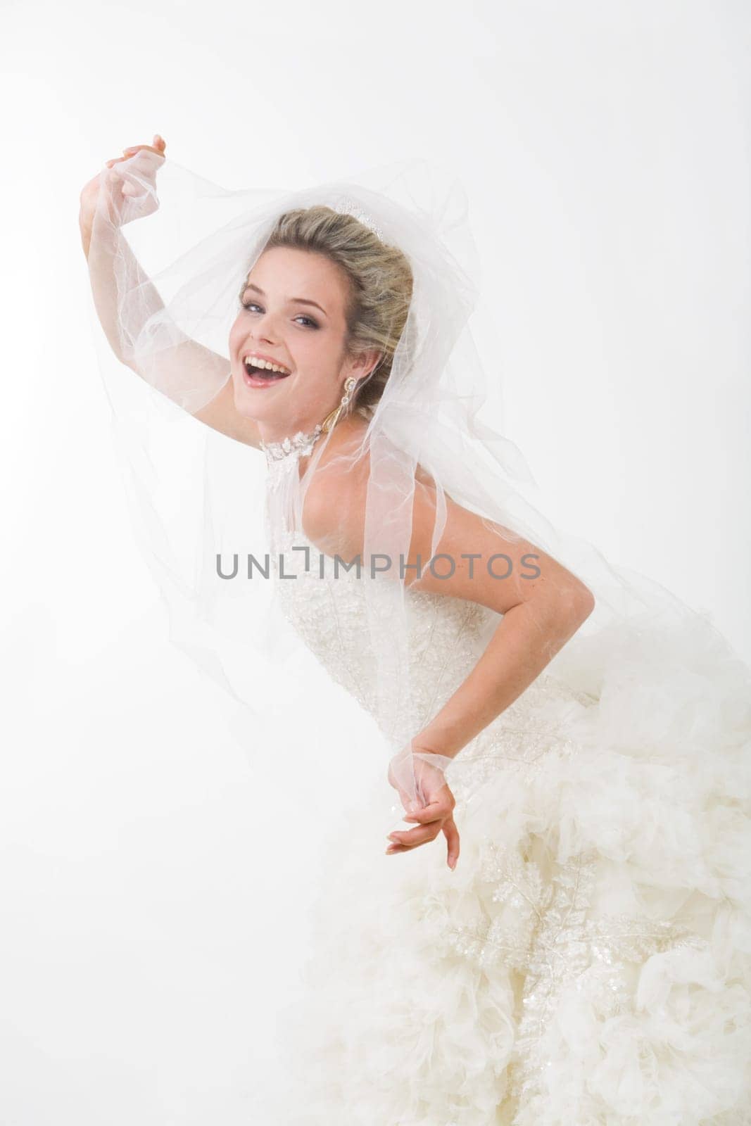 Photo of happy bride looking out of her veil and laughing at camera
