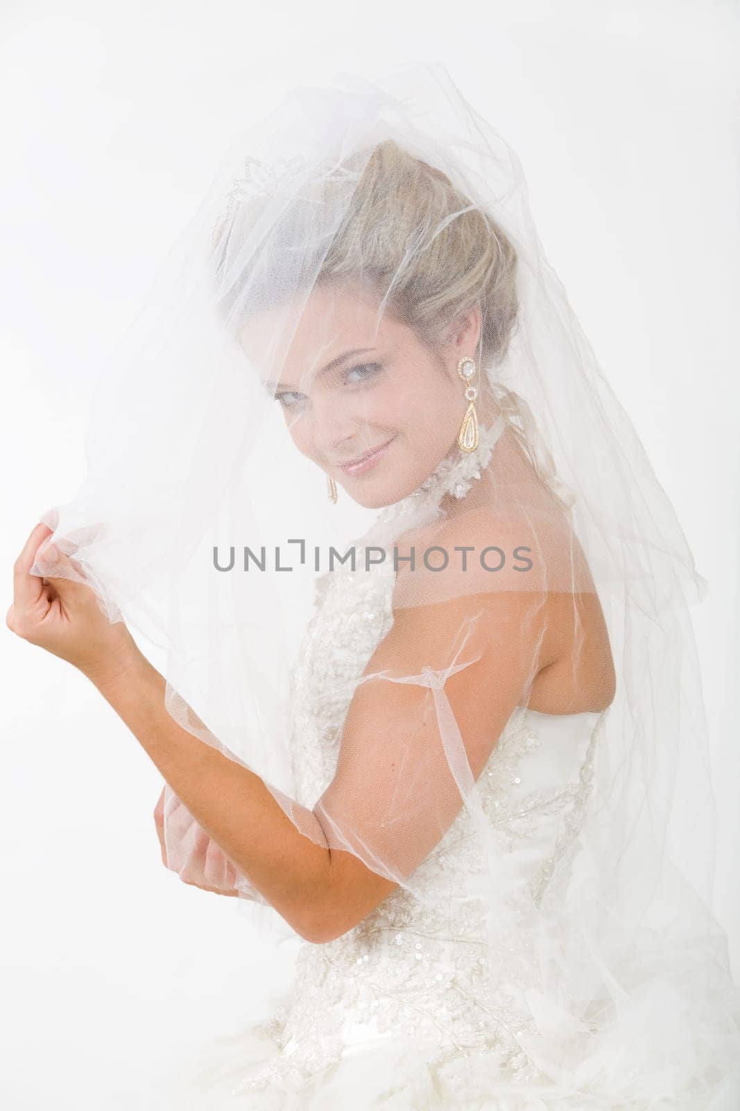 Portrait of happy bride looking at camera with smile through her veil