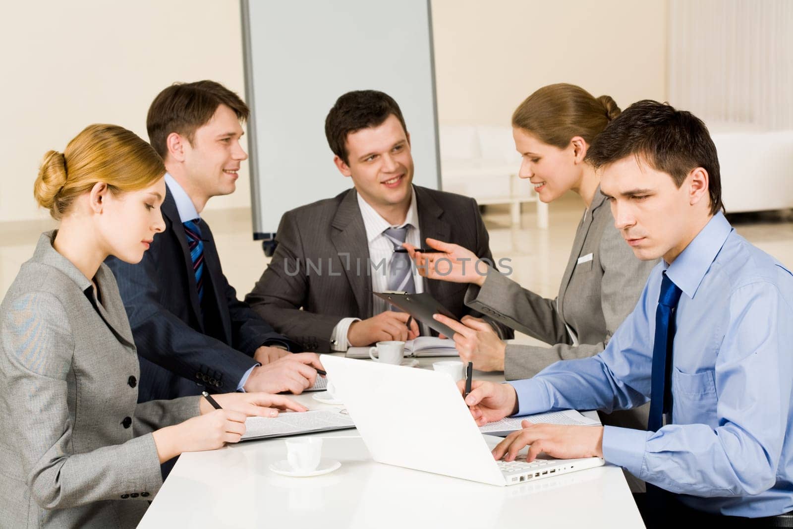 Portrait of confident colleagues working while confident woman sharing her idea with co-workers on background