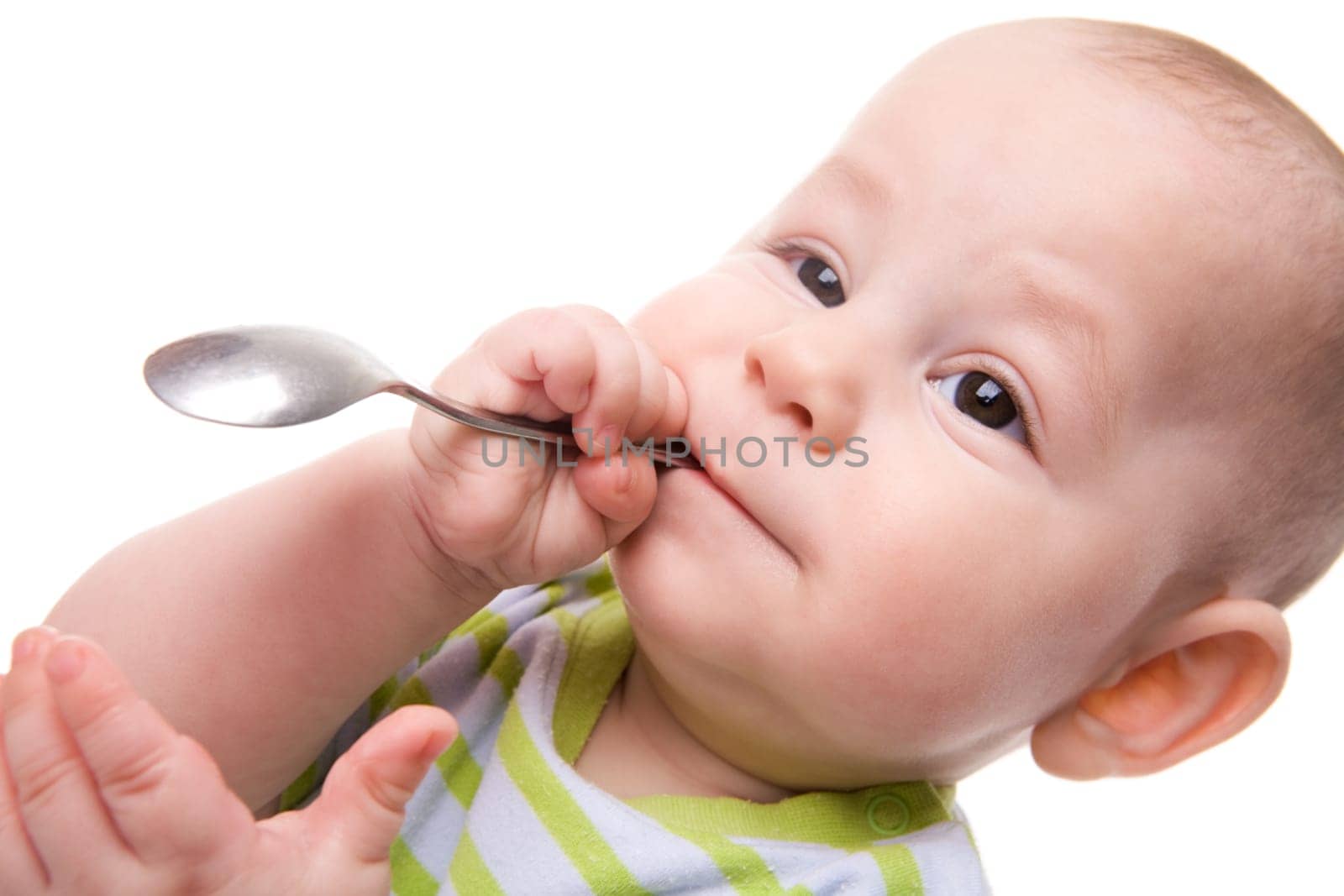 Close-up of adorable baby holding spoon and keeping it in his mouth