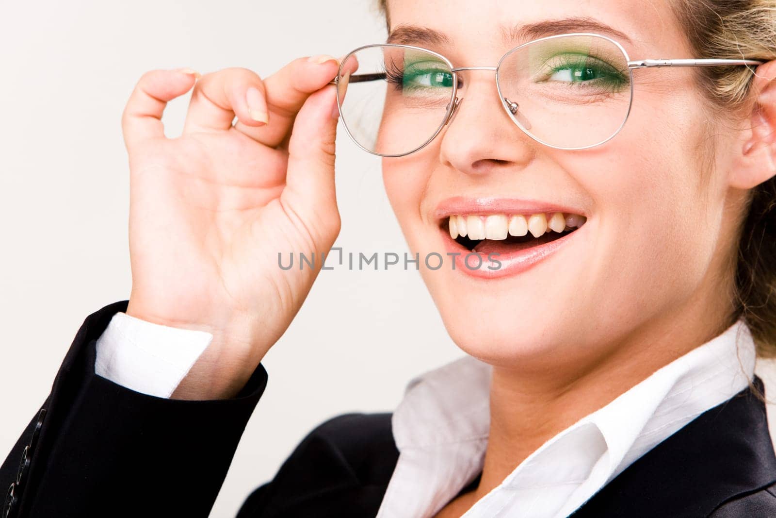 Close-up of happy woman wearing glasses and touching them while looking at camera