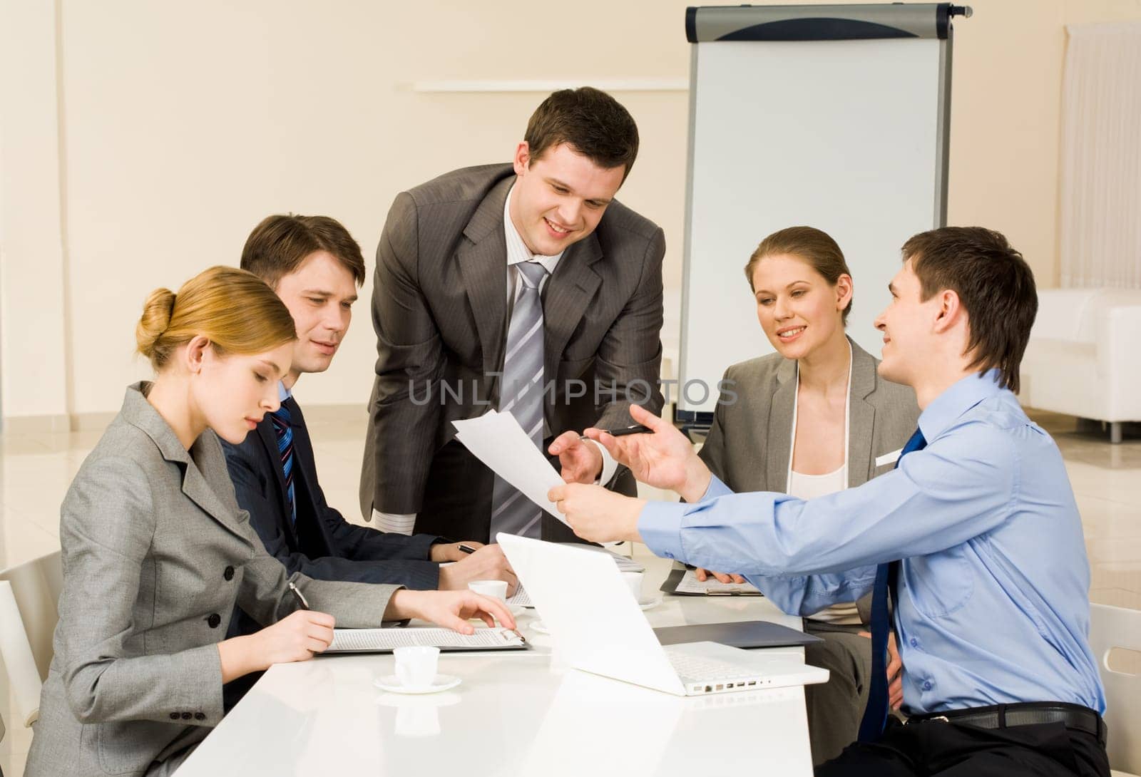 Portrait of confident man showing document to co-workers and interacting with them